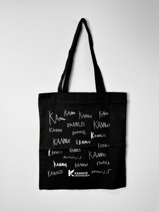 Musta kangaskassi, jossa valkoinen printti. Printti muodostuu 21kpl Kannus-teksteistä, jotka on kirjoitettu lasten käsialalla. Lisäksi printin alaosassa valkoisella Kannuksen Liikuntapalveluiden logo.